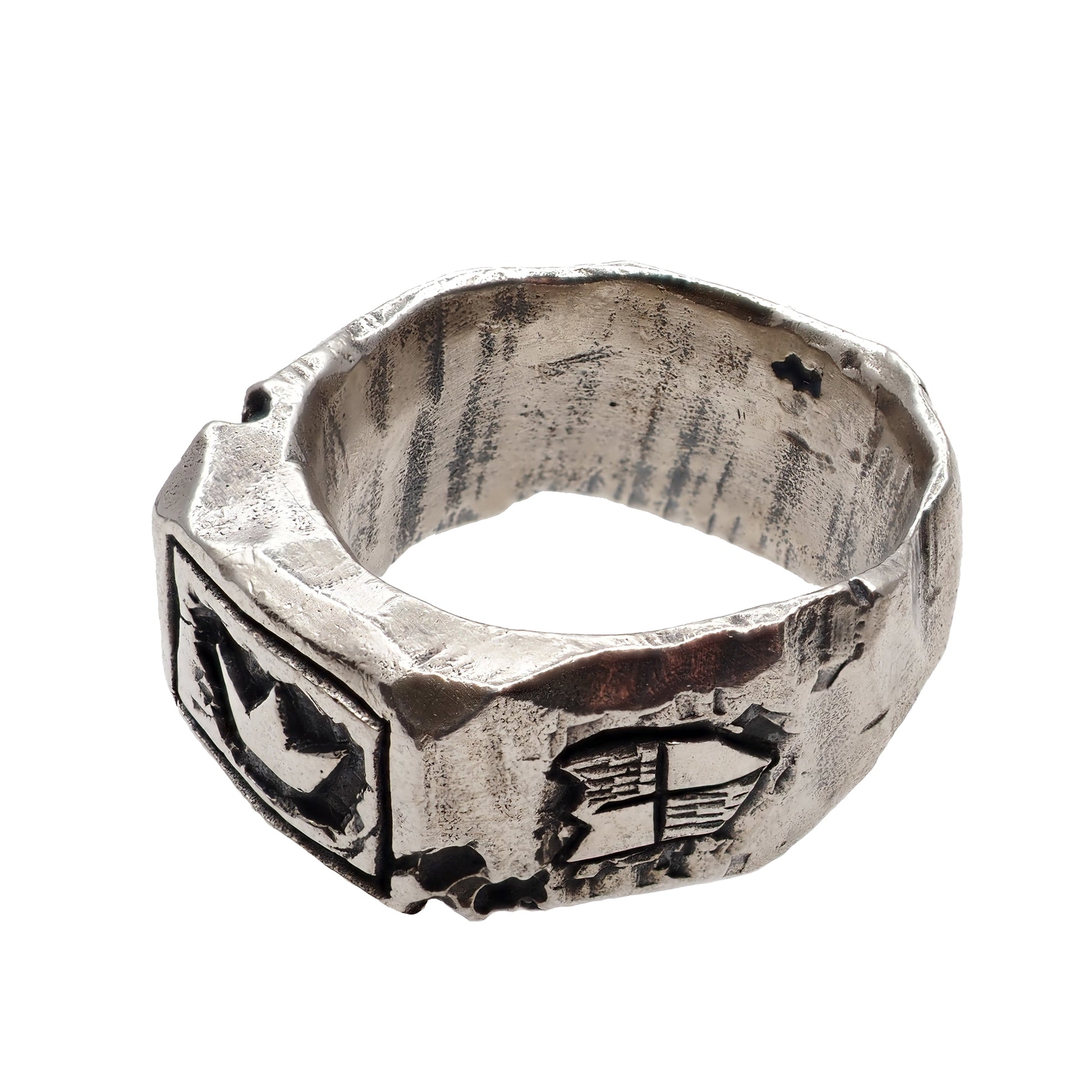 Silver ring of King Arthur with a crown in the foreground and a knight's shield on the right on a white background